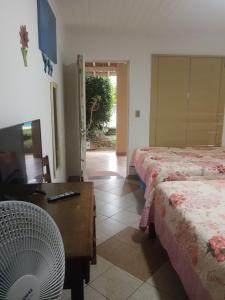 Cette chambre comprend deux lits, une table et une télévision. dans l'établissement Assahi, à Valinhos