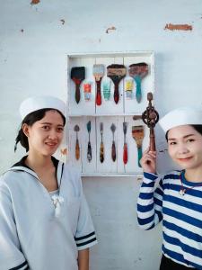 Duas raparigas com chapéus de marinheiro ao lado de uma prateleira de colheres. em The Oia Pai Resort em Pai