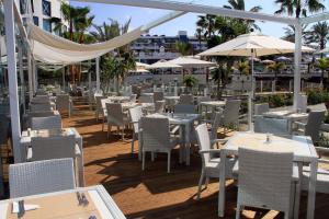 an empty restaurant with tables and chairs and umbrellas at Sandos Papagayo in Playa Blanca