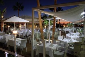 a restaurant with white tables and umbrellas at night at Sandos Papagayo in Playa Blanca