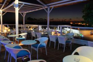 a restaurant with white tables and chairs at night at Sandos Papagayo in Playa Blanca