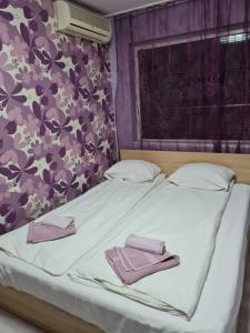 a bed with two towels on it with a purple wall at House Slava in Veliko Tŭrnovo