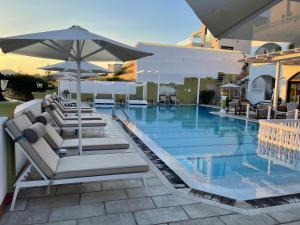 a swimming pool with lounge chairs and an umbrella at Fedra Mare in Agios Stefanos