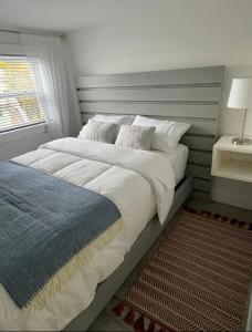 Un dormitorio con una gran cama blanca y una ventana en Squid Cove Cottage, en Pilleyʼs Island
