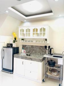 a white kitchen with a sink and a refrigerator at AIRPORT GUESTHOUSE DAVAO in Davao City
