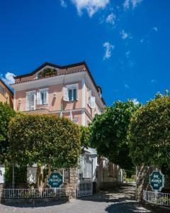 un bâtiment rose avec des arbres devant lui dans l'établissement Boutique Hotel Don Alfonso 1890, à SantʼAgata sui Due Golfi