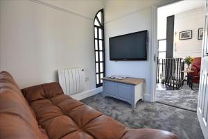 a living room with a couch and a flat screen tv at Engine House apartment - a Unique Holiday Home for 2 in Marazion