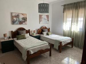 1 dormitorio con 2 camas y ventana en Casa das Laranjeiras, en Mértola