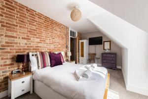 a bedroom with a bed and a brick wall at Villa Otto - Norfolk Holiday Properties in Cromer