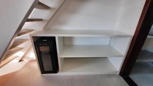 a white book shelf with a black computer on it at Bangalô Aconchegante de Frente para o Mar in Prado