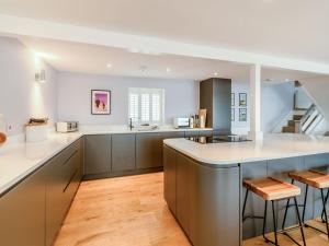 una cocina abierta con encimeras blancas y suelo de madera. en Point House en Milford Haven