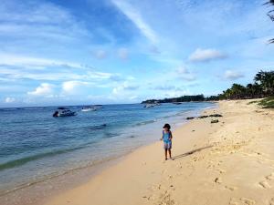 a young child standing on a beach near the water at Villa Pointe Aux Piments in Pamplemousses Village