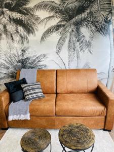 a brown couch in a living room with a palm mural at L'instant présent - Petite vue mer in Villers-sur-Mer