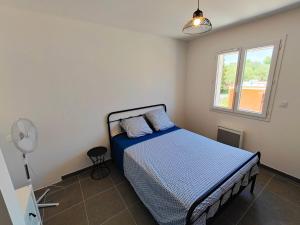 um quarto com uma cama com lençóis azuis e uma janela em Villa Vias Plage neuve em Vias