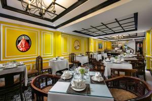 un restaurante con mesas y sillas blancas y paredes amarillas en Lavender Central Hotel & Spa Hanoi, en Hanói