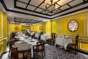 a restaurant with white tables and chairs and yellow walls at Lavender Central Hotel & Spa Hanoi in Hanoi