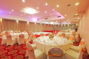 um salão de banquetes com mesas e cadeiras brancas em Kandyan Reach Hotel em Kurunegala