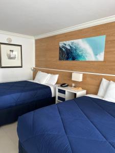two beds in a hotel room with blue sheets at Ocean Manor Tiki Sunset Retreat in Fort Lauderdale