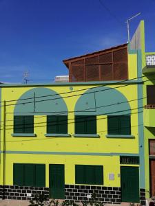 um edifício amarelo e verde com telhado castanho em Residencial Chez Flor em Porto Novo