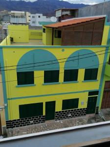 un edificio amarillo y azul con puertas verdes en Residencial Chez Flor en Porto Novo