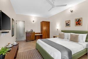 a bedroom with a large bed and a flat screen tv at La Vaiencia Beach Resort, Morjim Beach in Morjim