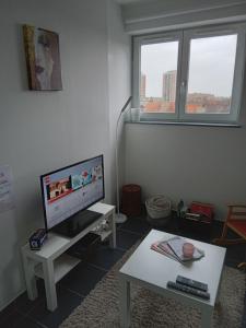 uma sala de estar com uma televisão numa mesa branca e uma mesa sidx sidx sidx em Roubaix près Lille, un cocon en plein centre em Roubaix