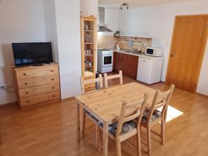 una cucina con tavolo in legno, sedie e TV di Chata Terezka a Kvilda