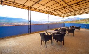a patio with tables and chairs and mountains in the background at Hotel TOURAGHINE in Chefchaouen