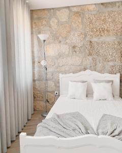 a bedroom with a white bed and a stone wall at Casa dos Avós in Castelo de Paiva