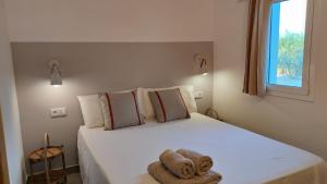a bedroom with a white bed with a towel on it at Mas Midó in Sant Jaume d'Enveja