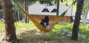 a girl sitting in a hammock in a yard at Golte SkiCenter Apartment in Mozirje