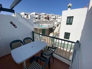 einen Balkon mit einem weißen Tisch, Stühlen und Gebäuden in der Unterkunft CASA MERY in Puerto del Carmen