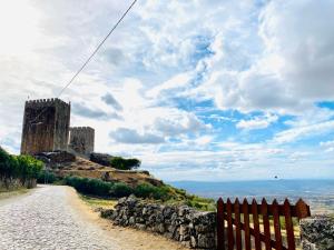 un castillo en una colina al lado de un camino de tierra en CASA DO PENEDO - Um Segredo na Serra da Estrela en Quintãs de Baixo