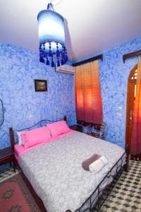 a bedroom with a bed with pink and blue walls at Hotel TOURAGHINE in Chefchaouene