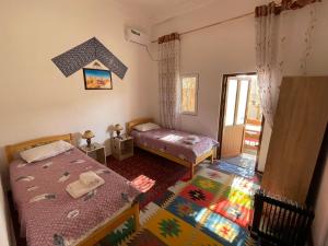 ヒヴァにあるGuest House Khiva BOYJON OTAの小さなベッドルーム(ベッド2台、窓付)