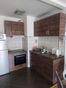 eine Küche mit Holzschränken, einer Spüle und einem Kühlschrank in der Unterkunft Stan na dan, Titanik Tuzla, centar grada in Tuzla