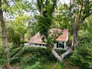 une maison blanche avec un toit rouge dans les bois dans l'établissement Cottage Uylenhorst, De Witte Bergen 34, à IJhorst