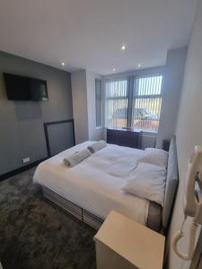 a bedroom with a large white bed and a window at Harrington House in Cleethorpes