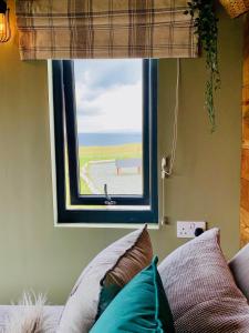 a window above a couch with a view of the ocean at Coral Cabins in Dunvegan