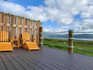 2 sillas sentadas en una terraza de madera con una valla en Coral Cabins en Dunvegan