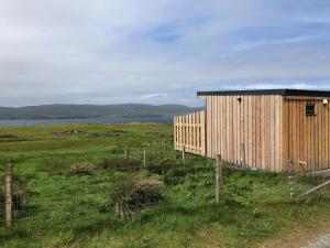 a wooden building in a field next to a fence at Coral Cabins in Dunvegan