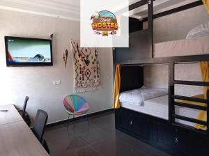 a bedroom with bunk beds with a tv and a table at Stork Marrakech Luxury Hostel in Marrakesh