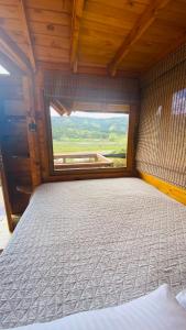 duże łóżko w pokoju z dużym oknem w obiekcie Villa Angela Glamping & Tiny Houses w mieście Paipa
