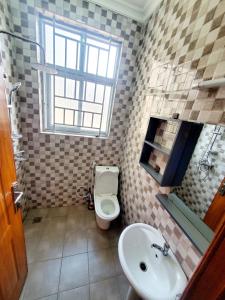 a bathroom with a toilet and a sink and a window at Ebenezer Hotel Apartments in Kigali