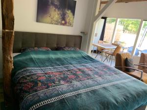 een slaapkamer met een bed met een groen dekbed bij Gastenverblijf 't Oelengoor in Sinderen