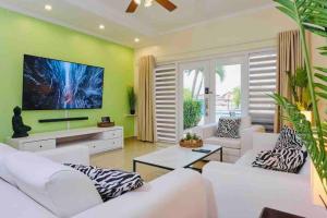 a living room with white furniture and green walls at Eagle Beach Aruba Breeze Condominium Lime in Palm-Eagle Beach