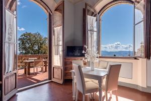 uma sala de jantar com mesa e cadeiras e janelas grandes em Appartamenti Villa Mascagni em Volterra