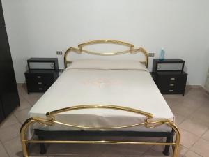 ein Bett mit einem goldenen Rahmen und zwei Nachttischen in der Unterkunft casa 102 in Finale Ligure