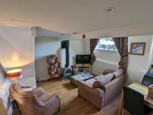 a living room with a couch and a tv at Pinfold Holiday Cottage in Skipton