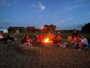 a group of people sitting around a fire in a field at The Fern at BrackenXcapes in Newark upon Trent